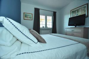马贝拉Cabopino Apartament, Marbella´s Beach的卧室配有带枕头的白色床和电视。