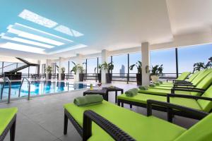 安曼安曼摄政宫酒店的一个带绿色椅子的泳池间和游泳池