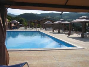 皮亚诺·德勒·皮耶韦阿西西及时行乐生活俱乐部酒店的一个带桌子和遮阳伞的大型蓝色游泳池