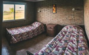 洛斯雷特斯El Retiro - Casa de campo en Los Reartes的一间设有两张床和砖墙的房间