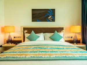 多哈Retaj Salwa Resort & Spa的一间卧室配有一张大床和两盏灯