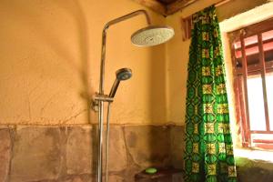 NyakinamaRed Rocks Rwanda - Campsite & Guesthouse的浴室设有绿色窗帘和淋浴