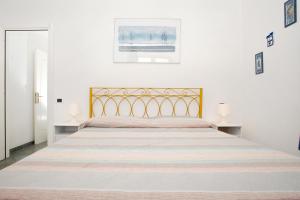 圣特雷莎加卢拉Bilocale Via Cairoli的白色卧室设有一张带金色床头板的大床