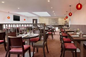 Easton in Gordano拉马达布里斯托尔西旅馆的餐厅设有木桌和红色椅子
