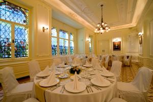 布达佩斯布达佩斯维多利亚精品酒店的宴会厅配有白色的桌椅和窗户