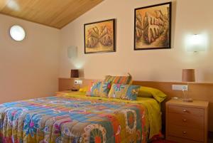 圣科洛马·德法尔品克斯酒店的卧室配有一张床,墙上挂有两张照片