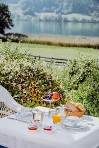魏森湖斯恩兹昂酒店的一张带饮料和一篮水果的白色桌子