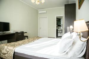 文尼察丘池尔酒店的一间卧室配有一张带书桌和灯的床。