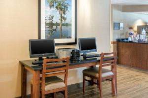 比洛克西Comfort Inn & Suites Biloxi-D'Iberville的一张桌子,配有两台电脑显示器和两把椅子