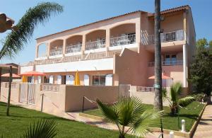 拉隆德莱丝莫里斯Argentiere-Club的一座大型粉红色建筑,设有阳台和棕榈树
