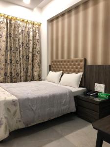 孟买Hotel Antique - Colaba的一间卧室配有一张大床和窗帘