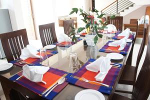 努沃勒埃利耶J's Villa的用餐室配有带盘子和餐巾的长桌