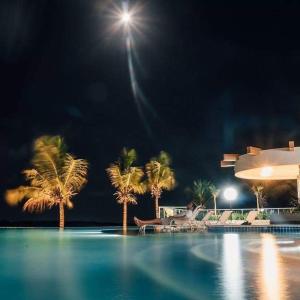萨利诺波利斯SALINAS PARK RESORT的棕榈树的夜间游泳池