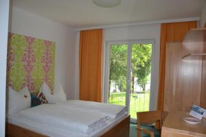 阿特湖畔努斯多夫达斯格拉芬古特酒店的一间卧室配有一张床、一张书桌和一个窗户。