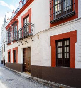 塞维利亚Suites Machado的一条白色和红色的建筑,在街上有一扇门