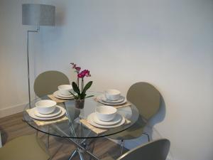 东基尔布赖德Westpark Apartment的玻璃桌,带盘子和杯子,花瓶