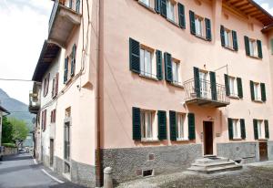 贝拉吉奥Locanda della Maria的街道上一座粉红色的建筑,设有绿色百叶窗