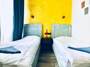 第比利斯City Center Loft by Happy Place的黄色墙壁的客房内的两张床
