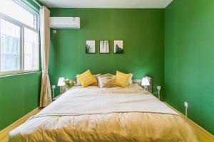 西安西安市莲湖区·回民街·路客精品公寓·00154940的绿色卧室配有一张带黄色枕头的大床