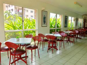 达尔文阿勒泰假日公寓酒店的餐厅设有红色的椅子和桌子以及窗户。