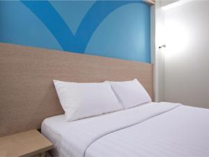 马尼拉Hop Inn Hotel Tomas Morato Quezon City的一张带白色床单和枕头的床