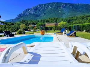 波尔维恩卡维亚克Hotel Restaurant Rose des Pyrénées的一个带白色躺椅的游泳池和一个山