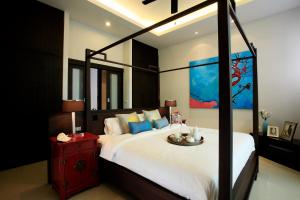 奈汉海滩Two Villas HOLIDAY - Onyx Style Nai Harn Beach, Phuket的一间卧室配有一张大床和一张大天蓬床,铺有四柱床。