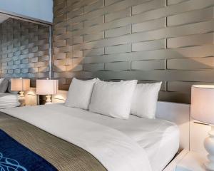 莱维顿列维敦康福特套房酒店的一间卧室配有一张带两盏灯的大型白色床。