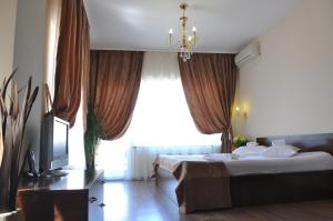 布加勒斯特胜利广场阿维酒店的一间卧室设有一张带电视和窗户的床。