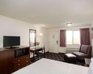 贝灵厄姆MorningGlory Inn & Suites的酒店客房配有一张床和一张书桌及一台电视