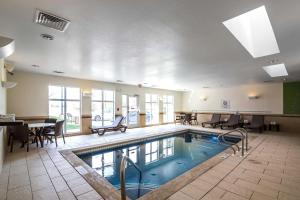 Haysville海斯维尔司丽普套房酒店的一个带椅子和桌子的大型室内游泳池