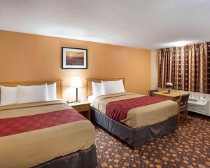 PhillipsburgEconoLodge Phillipsburg的酒店客房带两张床和一张桌子以及椅子。