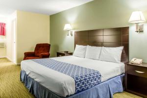 格罗顿格罗顿罗德威旅馆的酒店客房带一张大床和一把椅子