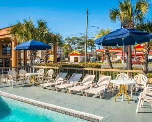 巴拿马城巴拿马城爱可诺汽车旅馆的一组椅子、桌子和遮阳伞,位于游泳池旁