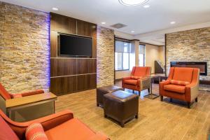 奥兰多Comfort Inn & Suites Kissimmee by the Parks的一间配备有橙色椅子和平面电视的等候室