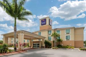 夏洛特港Sleep Inn & Suites Port Charlotte-Punta Gorda的一座建筑前有棕榈树的酒店