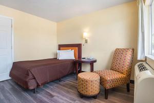 奥兰多Rodeway Inn Kissimmee Maingate West的配有一张床和一把椅子的酒店客房