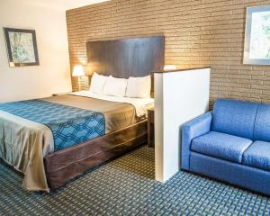 威尔明顿Rodeway Inn & Suites Wilmington North的酒店客房,配有一张床和一张蓝色椅子