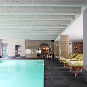 赫斯登-佐尔德尔皮茨酒店的一个带椅子和桌子的房间的游泳池