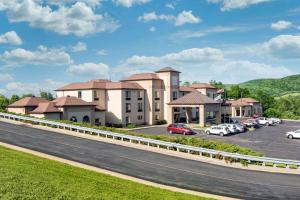 库珀斯敦Comfort Inn & Suites Milford - Cooperstown的停车场内停放汽车的大型建筑