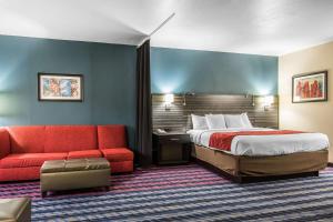 俄克拉何马城Comfort Suites Fairgrounds West的酒店客房,配有一张床和一张红色的沙发