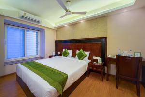 加尔各答Treebo Trend Vedanta的一间卧室配有一张床、一张书桌和一个窗户。