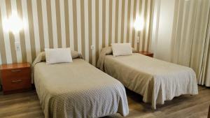 梅里达阿纳斯旅馆的配有条纹墙壁的酒店客房内的两张床