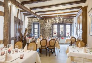 维安登Logis Hotel-Restaurant Petry的一间带桌椅和石墙的餐厅