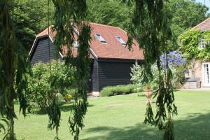 赫特福德Wellrose Barn的一座带绿草和树木的庭院