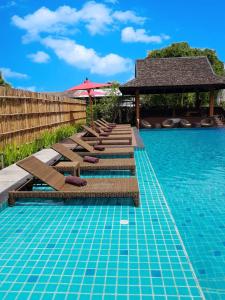 清莱PAN KLED VILLA eco hill resort - SHA extra plus的一个带躺椅和遮阳伞的游泳池