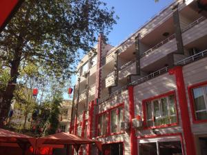 安塔利亚雅尔新奥特尔酒店的一座建筑,有红色的窗户,还有一棵树和遮阳伞