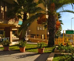 卡利亚里乌利维Ë帕尔梅住宅酒店的一群棕榈树在一座建筑前