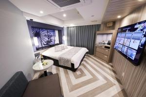 大阪Hotel Sen (Adult Only)的配有一张床和一台平面电视的酒店客房