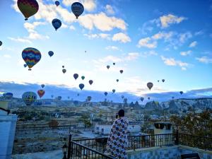 格雷梅Cappadocia Elite Stone House的一个人正在看着一束热气球